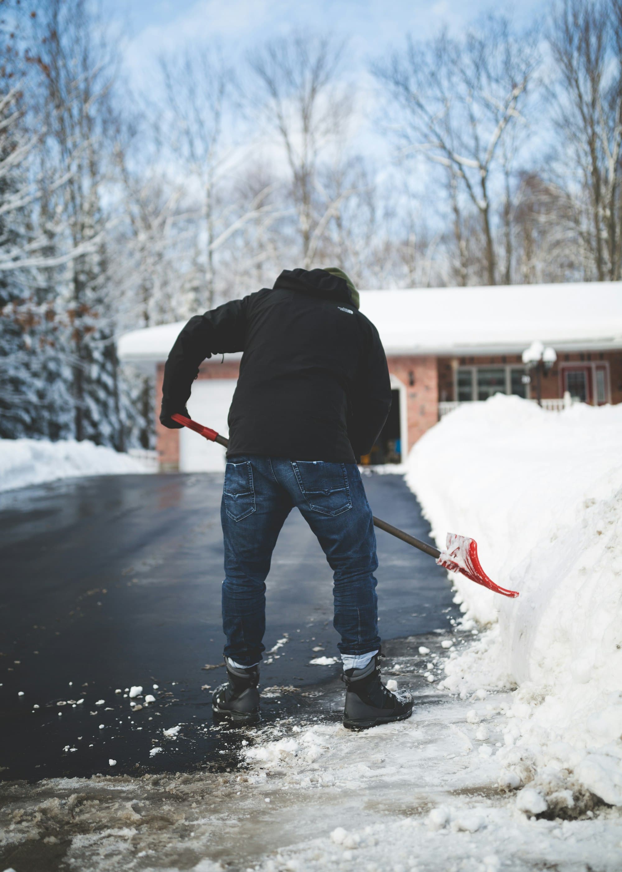 A cleared residential driveway with snow piled along the edge